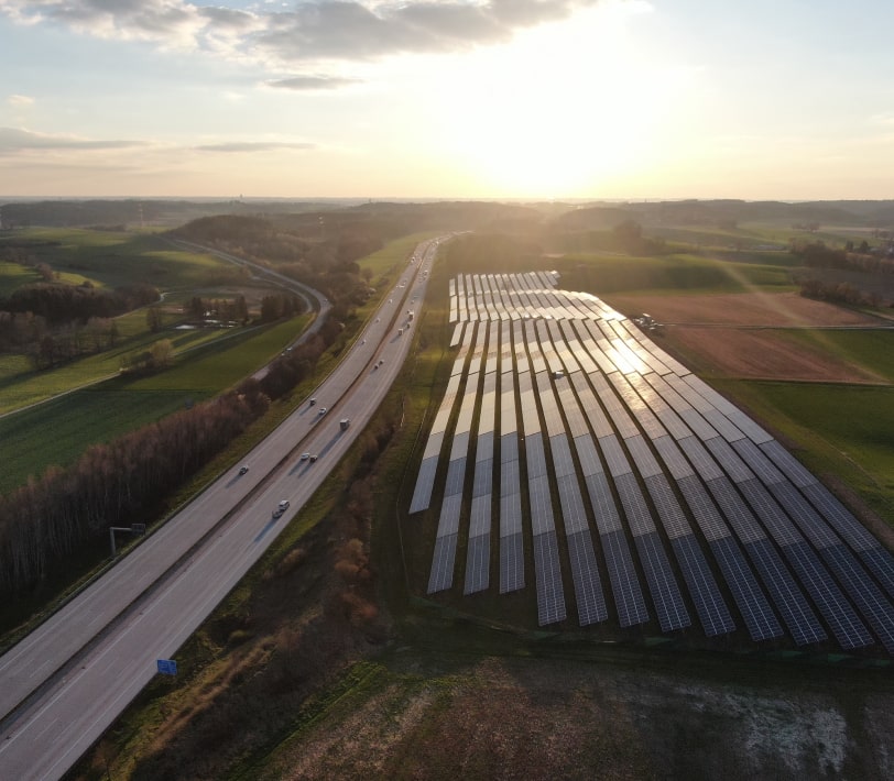 Solar panels on a field next to a highway.
