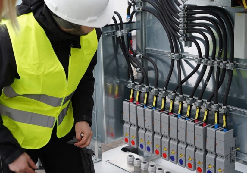 Mitarbeiter der TRICERA energy vor Schaltungen eines Batteriespeichers