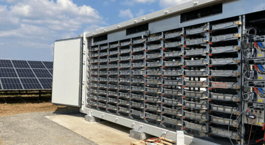 Geöffneter Outdoor-Batteriespeicher nahe eines Photovltaik-Anlagen-Feldes